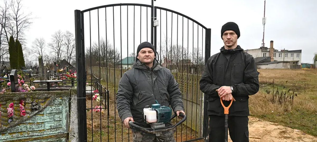 рабочие стоят возле кладбища с ломатами