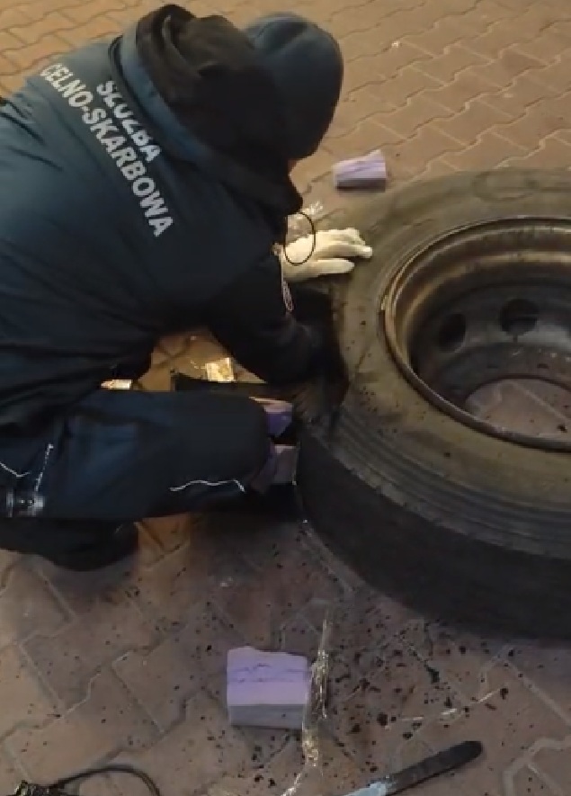 Польский таможенник достает сигареты из колеса автобуса. Фото: lubelskie.kas.gov.pl